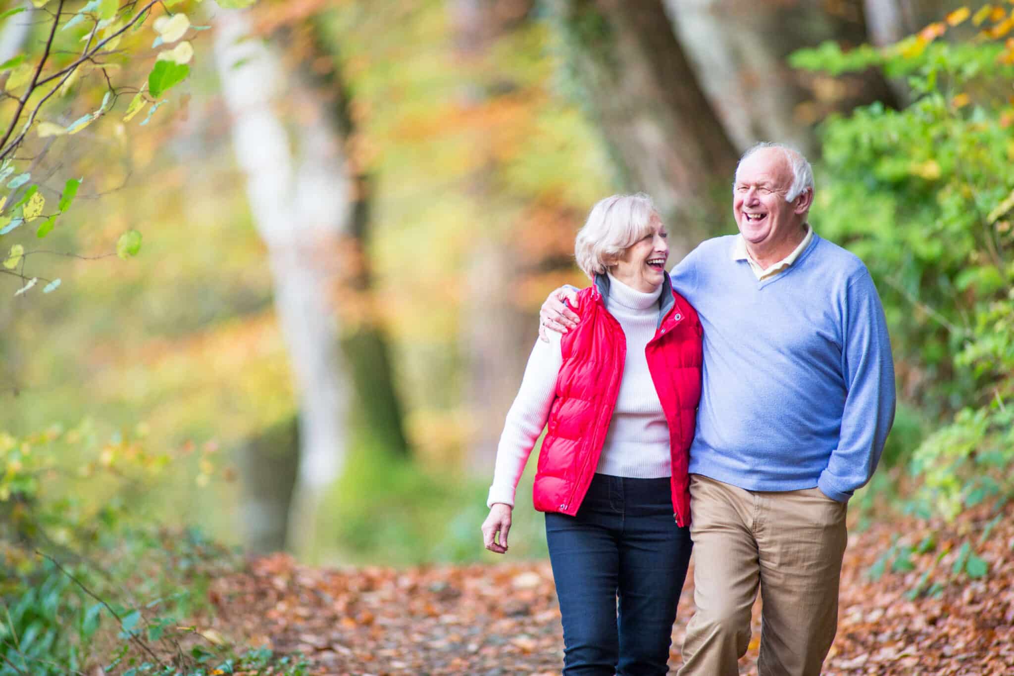 Older man and woman walking together on a trail in the woods