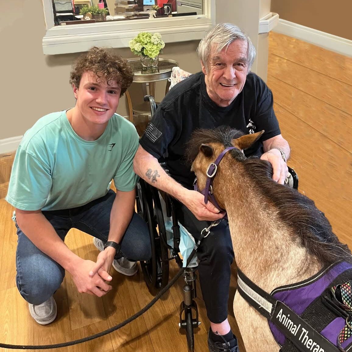 Volunteer Blake sitting next to hospice patient and miniature therapy horse at a visit. Permission received to use photo.